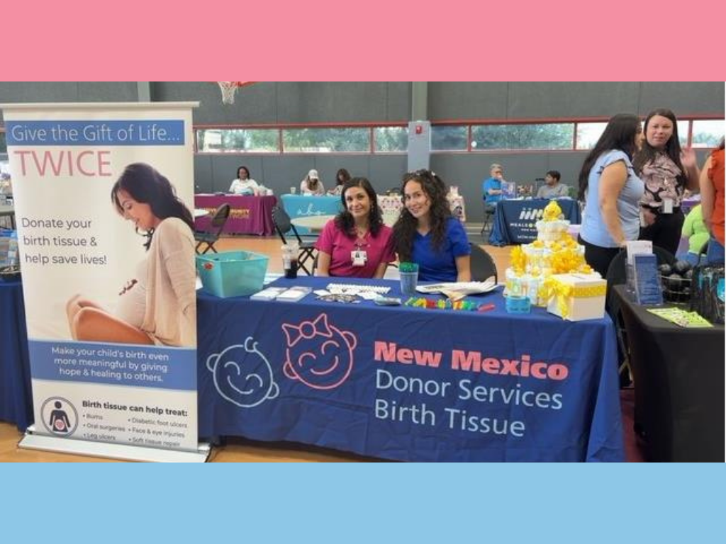 Women sit and smile at table during event.